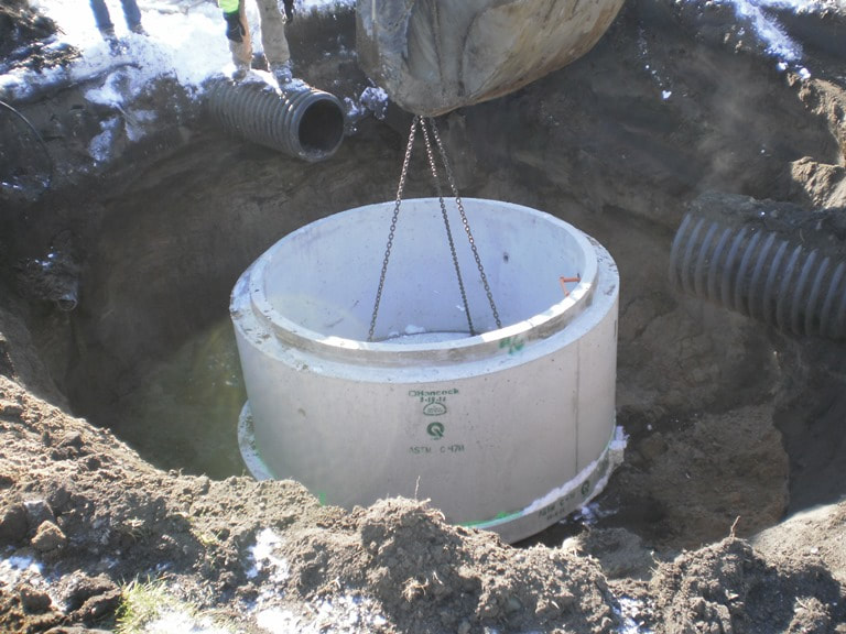 concrete basin getting lowered into excavated earth